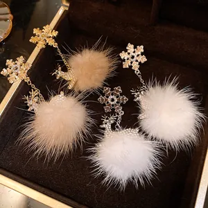 Dettaglio dei orecchini con fiocco di neve, renna e morbidi pompon di pelliccia.
