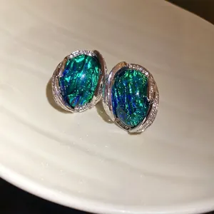 Eleganti orecchini in resina verde iridescente con montatura geometrica in diamanti.