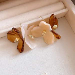 Gros plan de boucles d'oreilles fleurs en acrylique élégantes, tons ambre et crème