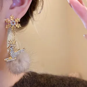 Dettaglio di orecchini natalizi eleganti con una renna di strass e un pompon di pelliccia.