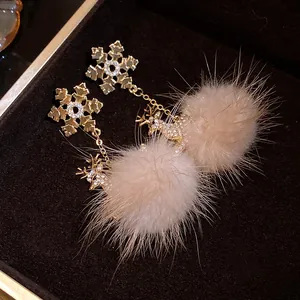 Dettaglio orecchini a fiocco di neve con strass e pompon di pelliccia sintetica beige