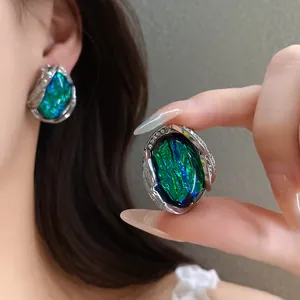 Dettaglio di orecchini geometrici in resina con anima iridescente e bordo strass