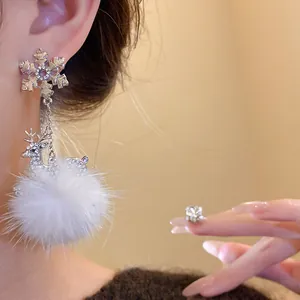 Dettaglio ravvicinato di orecchino pendente in argento con fiocco di neve e pompon bianco