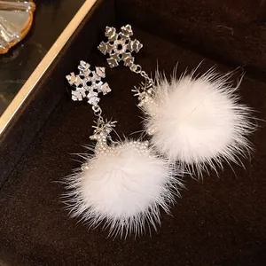 Dettaglio di orecchini a fiocco di neve con cervi di strass e pompon di pelliccia