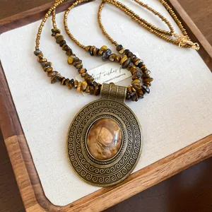 Detailed view of vintage Tiger Eye stone pendant necklace with beaded chain on tray.