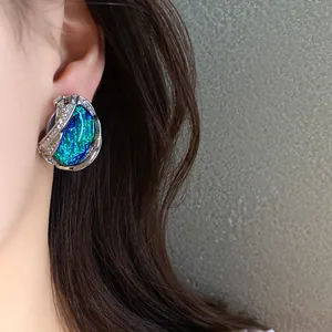 Primo piano di un elegante orecchino geometrico in resina d'argento con strass sull'orecchio