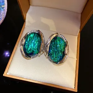 Primo piano di orecchini geometrici in resina verde con pietre in una scatola regalo