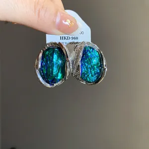Dettaglio di orecchini geometrici in resina verde effetto conchiglia e strass eleganti