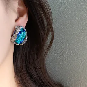 Primo piano di orecchini geometrici in resina con bordo argento e cristalli