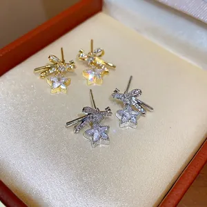 Primer plano de los pendientes de lazo y estrella de circonita en tonos oro y plata.