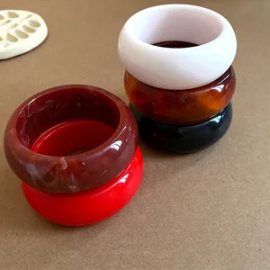 Group of colorful vintage chunky resin bangles stacked on a brown textured background.