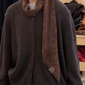 Nahaufnahme einer Vintage-Paisley-Stoff-Halskette kombiniert mit einem braunen Cardigan