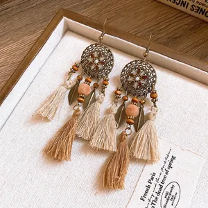 Primo piano di orecchini boho con nappe e foglie di resina in tonalità calde