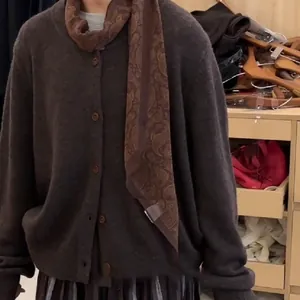 Detailansicht eines böhmischen Paisley-Seidenschals über einem braunen Cardigan