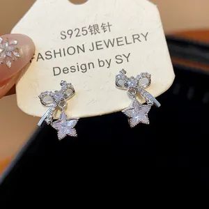 Detalle de pendientes de lazo y estrella de circón en tarjeta de aguja de plata S925.