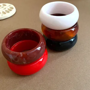 Macro detail of thick retro acrylic resin bangles in amber, red, and white finishes