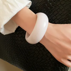 Close-up of a vintage minimalist white wide resin bangle bracelet on a female wrist