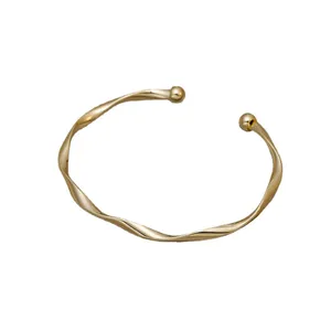Elegante bracciale rigido dorato minimalista ritorto geometrico con estremità a sfera tonda