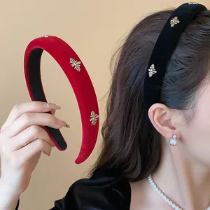 Close-up detail of red and black padded velvet headbands with golden bee accents
