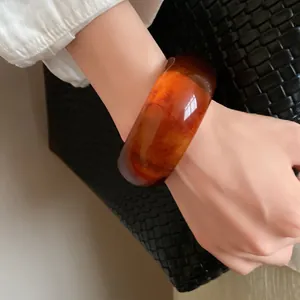 Close-up detail of a vintage amber marbled resin bangle bracelet with ink-wash texture