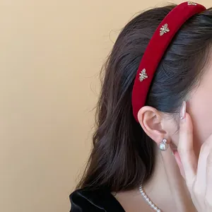Detailed close-up of a red velvet headband featuring elegant golden bee accents