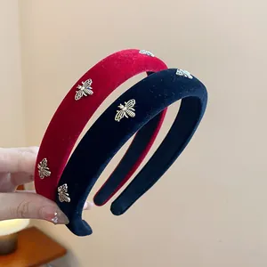 Detail shot of elegant red and black velvet headbands featuring golden bee accents