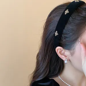 Close-up detail of a stylish black velvet headband with elegant gold bee ornaments