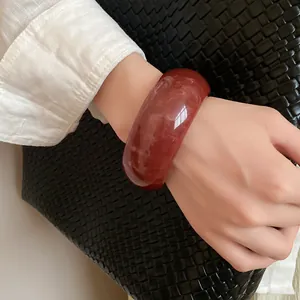 Vintage marbled red resin bangle shown on a wrist against a woven background.