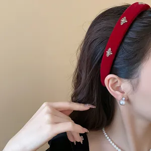 Detailed side view of a red velvet headband with elegant silver metal bee accents