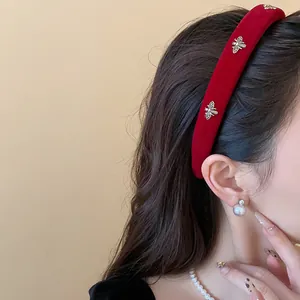 Detailed view of a red velvet headband with golden bee accents worn by a female model