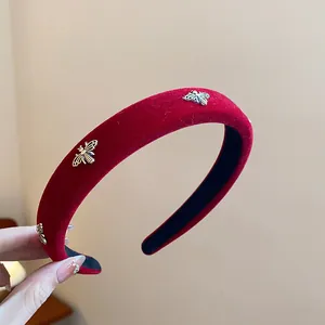 Close-up of a premium red velvet headband featuring delicate golden bee metal accents.
