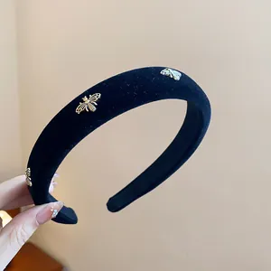 Close-up detail of a premium black velvet headband with golden honey bee embellishments