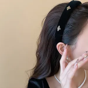 Close-up view of a stylish black velvet headband with golden bee ornaments on a model.