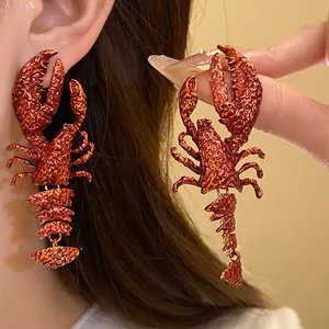 Nahaufnahme von originellen orange-roten Hummer-Ohrring-Anhängern mit Metalltextur
