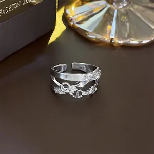 Close-up macro shot of a silver-tone geometric open ring with pavé zircon details on a dark background