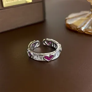 Close-up detail of silver-plated open ring featuring pink heart gems and baguette zircons