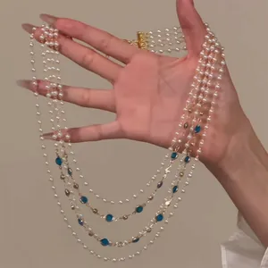 Detail of elegant multi-strand pearl necklace with blue gemstone accents and gold clasp