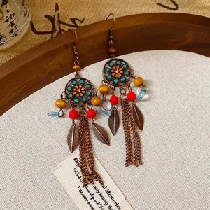 Dettaglio di orecchini etnici boho con nappe, ciondoli a foglia e perline colorate