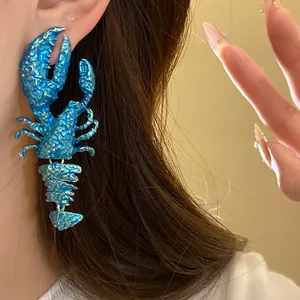 Nahaufnahme eines blauen Hummer-Ohrrings mit segmentiertem Schwanz an einem Modell.