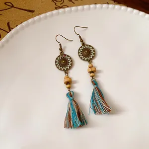 Vista dettagliata di orecchini etnici boho con nappe in filo di cotone e ganci in bronzo