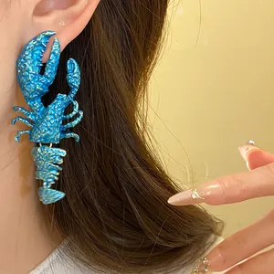 Nahaufnahme eines blauen Hummer-Anhängers am Ohr eines Models für Urlaubsstimmung