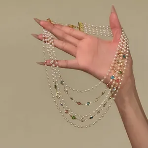 Detail of multi-layer pearl necklace with colorful gemstones in vintage style.