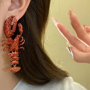 Detailaufnahme eines kreativen orangefarbenen Hummer-Ohrrings am Ohr eines Models