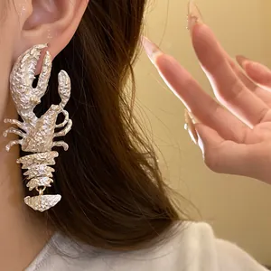 Nahaufnahme von silbernen Hummer-Ohrhänger am Ohr, einzigartiger Statement-Schmuck.