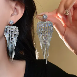 Close-up of zircon heart tassel earrings with silver pins and long sparkling fringe
