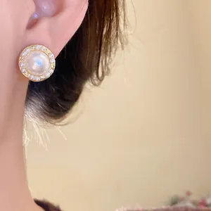 Primer plano de un elegante pendiente de perla redondo de estilo francés vintage puesto