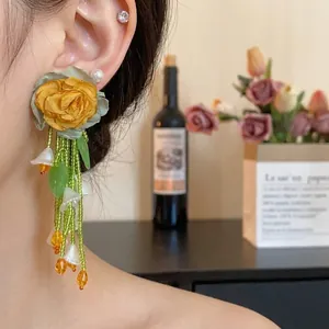 Forest style floral tassel earrings featuring yellow fabric rose and green bead tassels