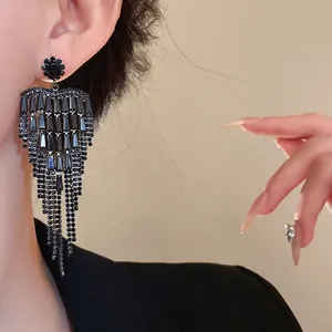 Close-up of elegant black tassel earrings with sparkling rhinestones for evening wear.