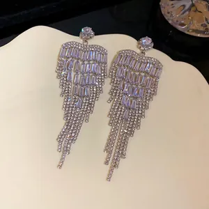 Detail of elegant silver zircon heart tassel earrings on a wavy plate