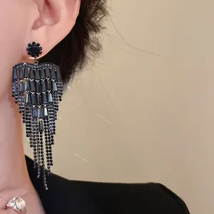 Detailed macro shot of elegant black zircon tassel heart earrings on a model